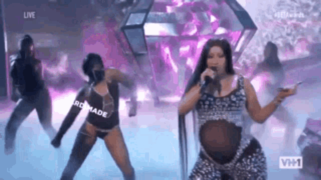 a pregnant woman is singing into a microphone while dancing on stage .