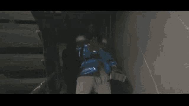 a man in a blue jacket is standing in a hallway .