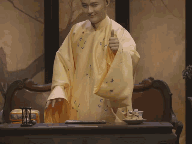 a man in a yellow robe giving a thumbs up sign