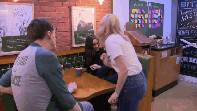 a group of people are sitting at a table with a man wearing a shirt that says " good for the house "