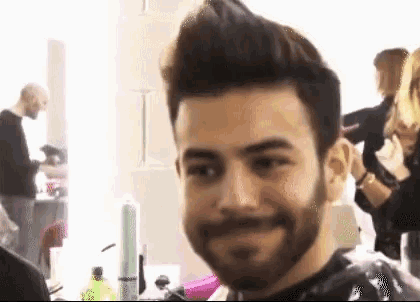 a man with a beard is smiling while getting his hair cut