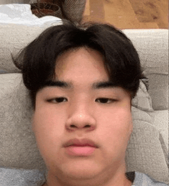 a young man is sitting on a couch and making a funny face .