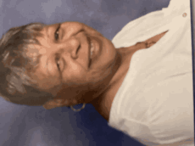 a woman in a white shirt is smiling and looking at the camera