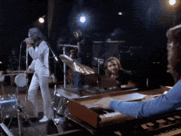 a man playing a keyboard in front of a group of musicians