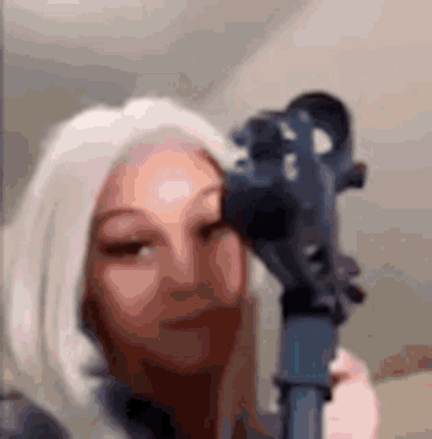 a woman is holding a gun to her face .