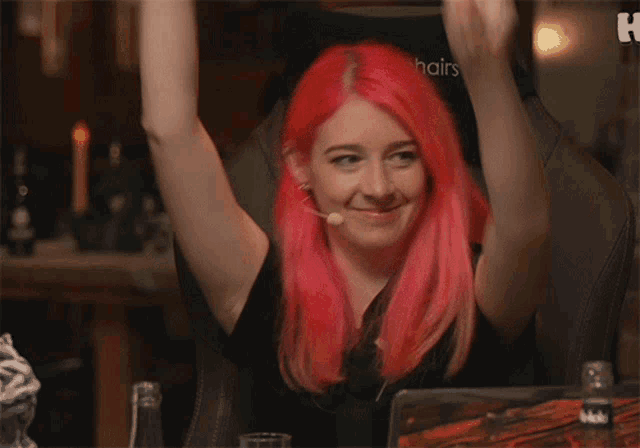 a woman with pink hair is sitting in a chair with the letter h on the back