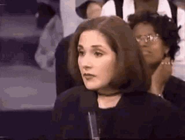 a woman is sitting in front of a microphone in a crowd .