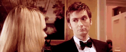 a man in a tuxedo and bow tie is talking to a woman .
