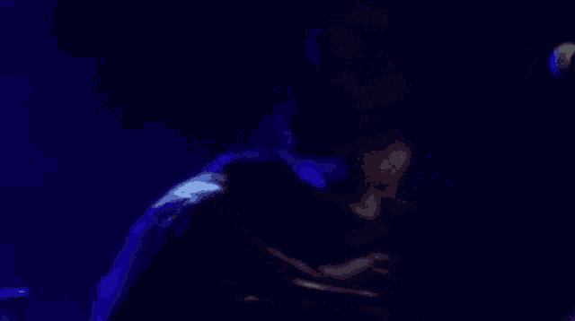 a woman singing into a microphone with a blue light behind her