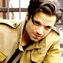 a close up of a man wearing a tan jacket and a black shirt .