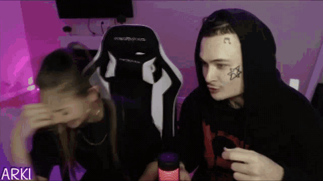 a man with a star tattoo on his face sits next to a woman who is covering her face