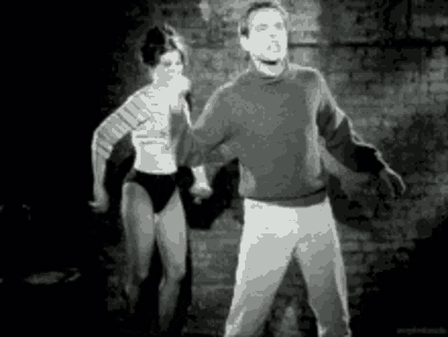 a man and a woman are dancing together in front of a brick wall .