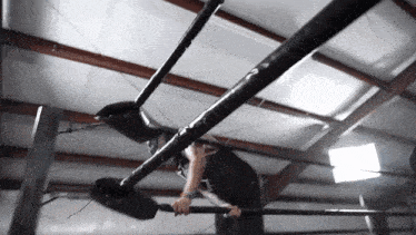 a man is hanging upside down on a bar in a ring