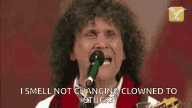a man singing into a microphone with the words i smell not changing clowned to stuck written below him