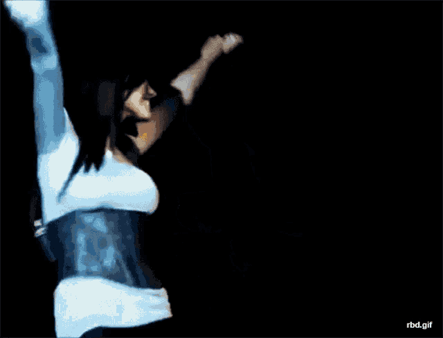a woman in a blue top is holding a microphone while dancing with a man in a blue shirt