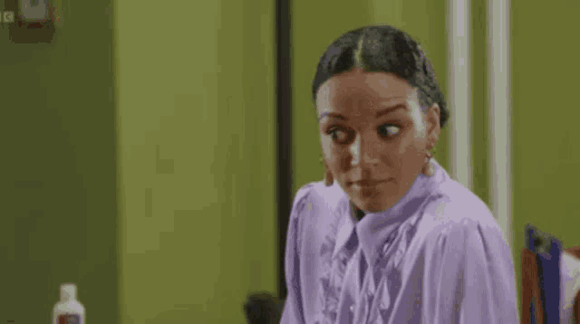 a woman in a purple shirt is sitting in front of a mirror .