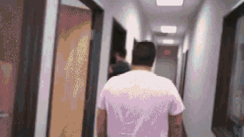 a man in a pink shirt is walking through a hallway