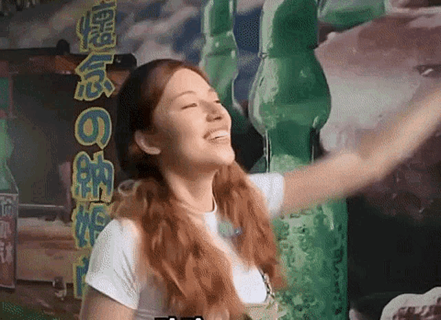 a woman is smiling in front of a sign that says ' coca cola ' on it