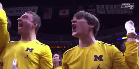 two men wearing yellow shirts with the letter m on them are cheering