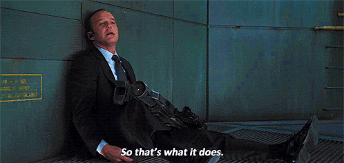 a man in a suit and tie is laying on the ground with a gun and says so that 's what it does