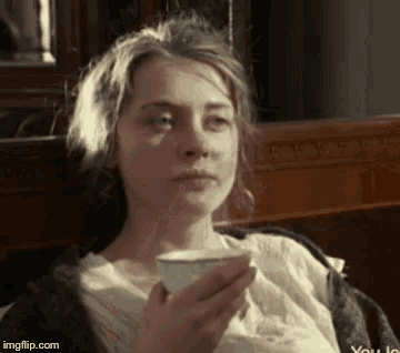 a woman is sitting in a chair drinking a cup of coffee .