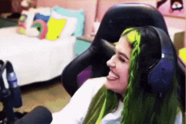 a girl with green hair is wearing headphones and smiling