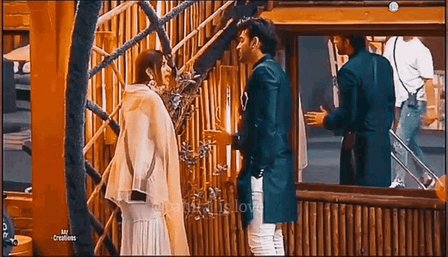 a man and a woman are standing next to each other in front of a bamboo fence .