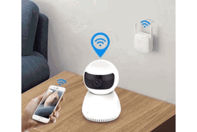 a person is holding a cell phone next to a wireless camera on a table .