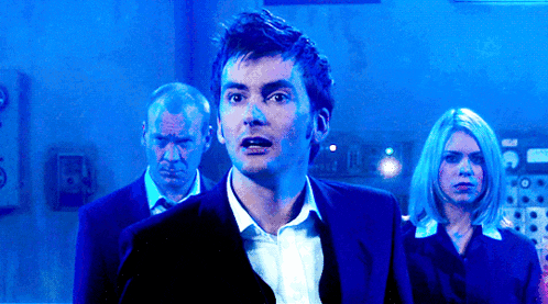 a man in a suit stands in front of a blue wall