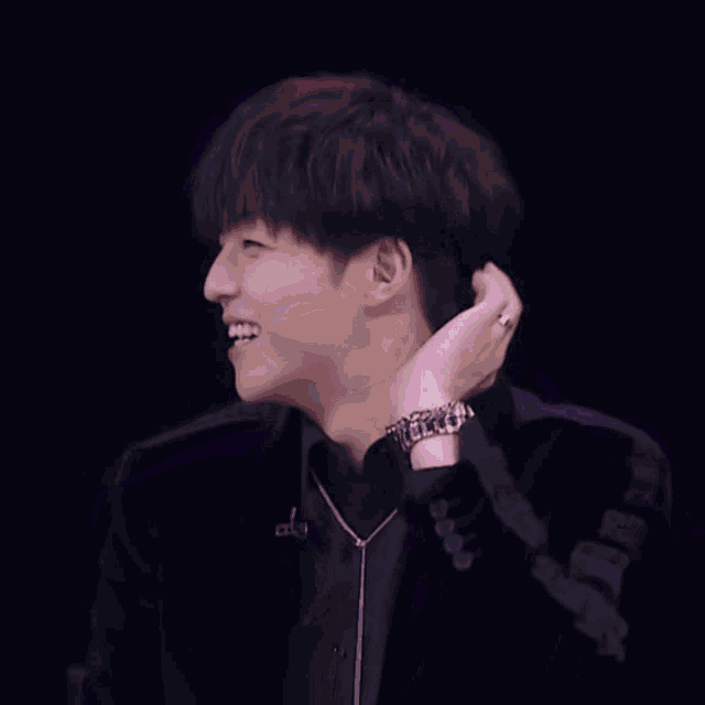 a young man with purple hair is laughing and holding his neck