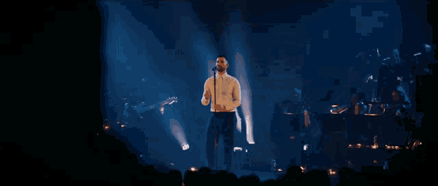 a man singing into a microphone on a stage in front of a crowd