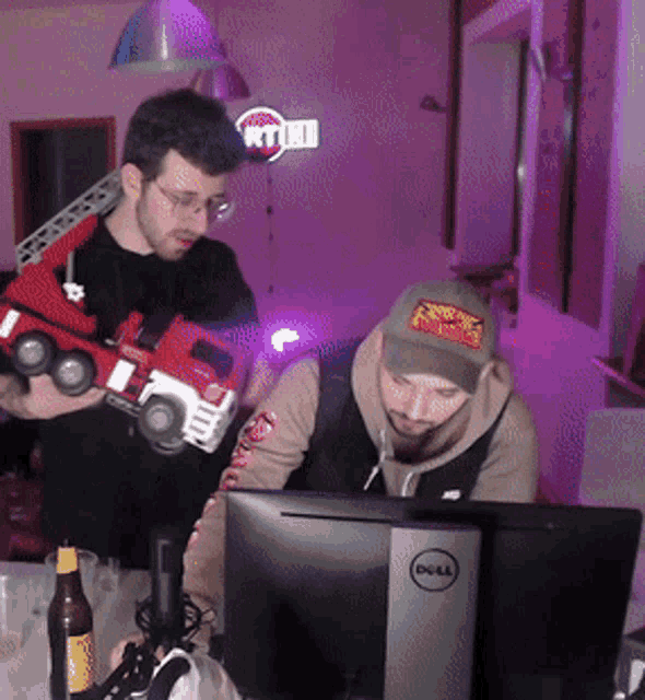 a man holding a toy truck looks at a dell monitor