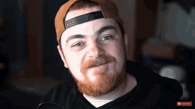a man with a beard wearing a hat with a subscribe button on the bottom