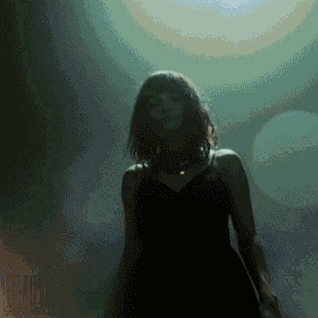 a woman in a black dress stands in front of a green background