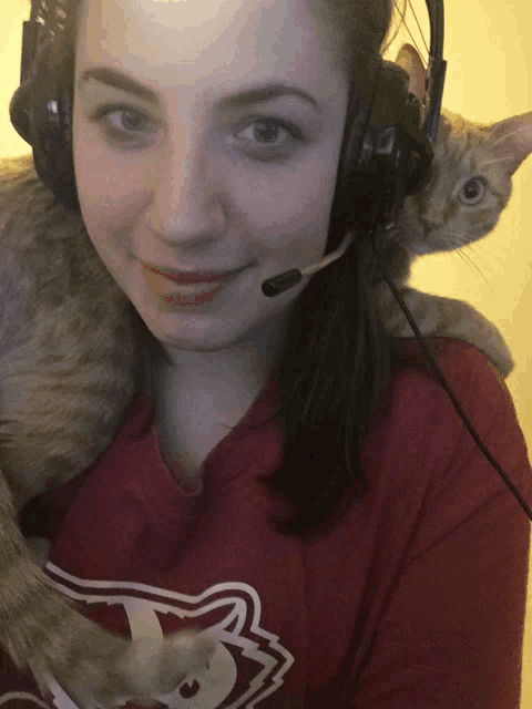 a woman wearing headphones and holding a cat
