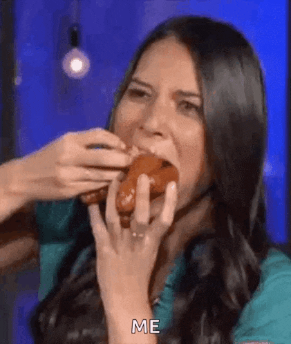a woman is eating a donut with her hands while another woman feeds her a donut .