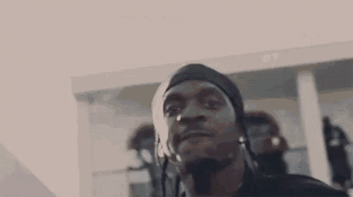 a man wearing a bandana and earrings is standing in front of a group of people .