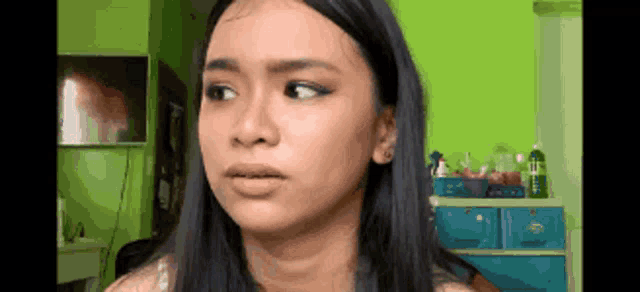 a young woman with long black hair is making a funny face in a room .