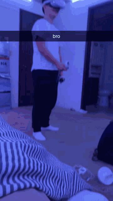 a man wearing a virtual reality headset is holding a remote control and says bro