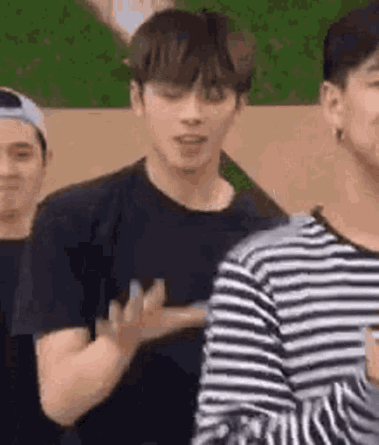 a group of young men are standing next to each other and one of them is wearing a black and white striped shirt .