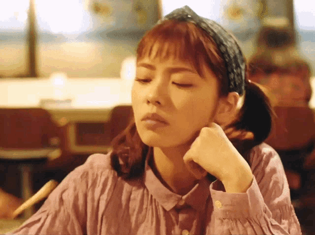 a woman wearing a headband and a pink shirt is sitting at a table