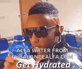 a man wearing sunglasses and holding a bottle of water .