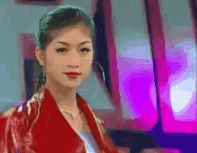 a woman in a red jacket is standing in front of a purple light .
