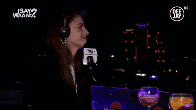a woman wearing headphones holds a microphone in front of a sign that says deejay
