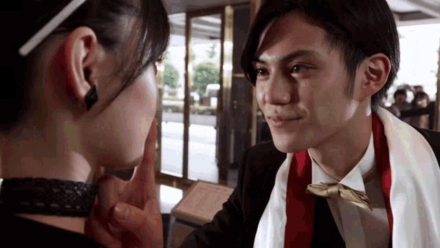 a woman touches a man 's face while he wears a bow tie