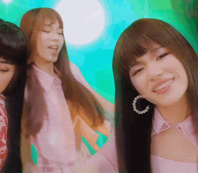 a woman wearing a pink shirt and pearl hoop earrings smiles for the camera
