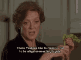 a woman is eating a sandwich and saying " those yankees like to make us out to be alligator wrestling biggies "
