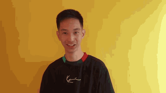 a young man wearing a black karl kani shirt