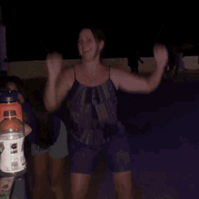 a bottle of gatorade sits on a table next to a woman dancing