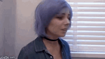 a woman with purple hair is wearing a choker and a denim shirt .